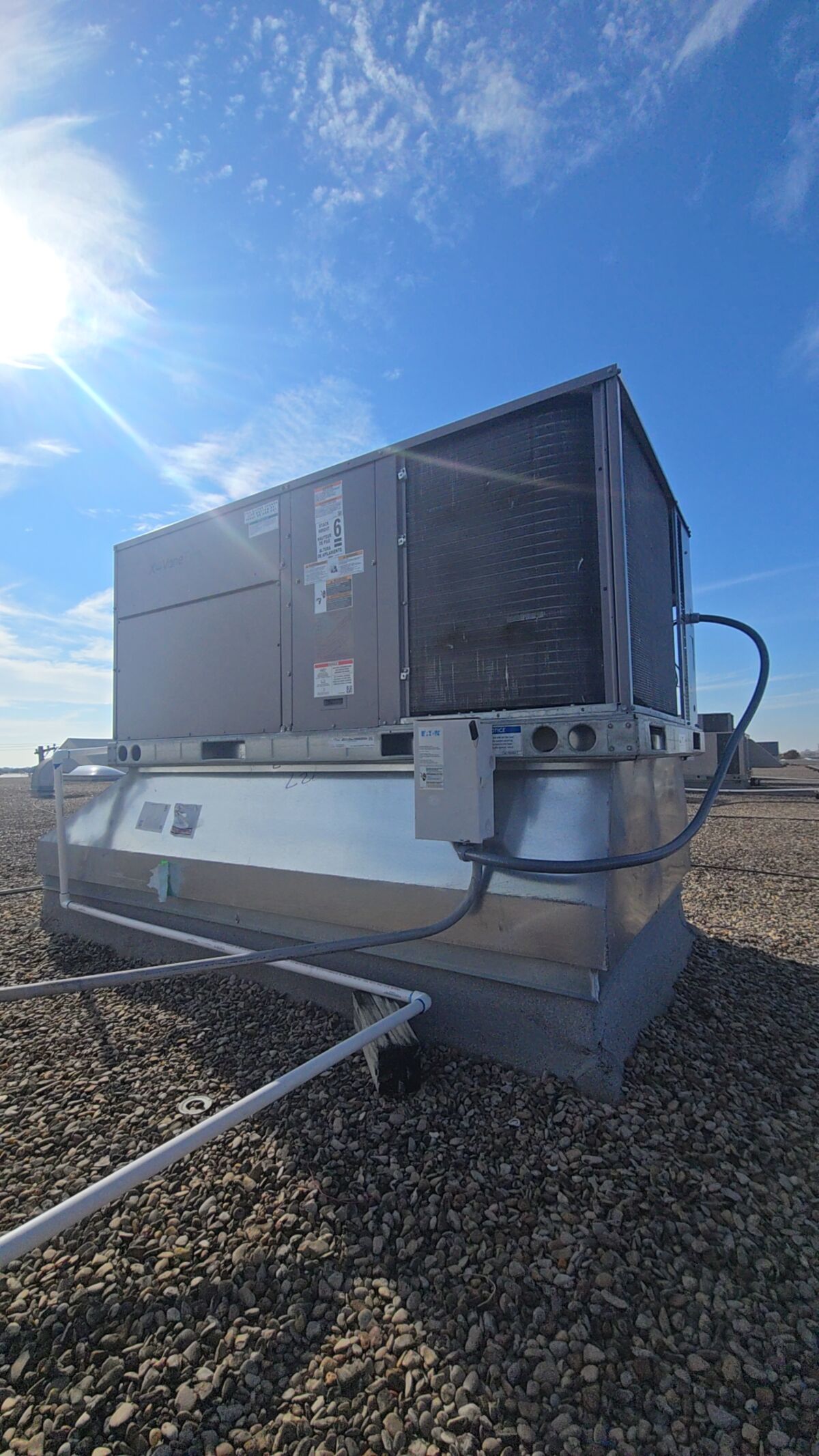 Packaged rooftop air conditioning unit on a flat commercial roof under bright sun