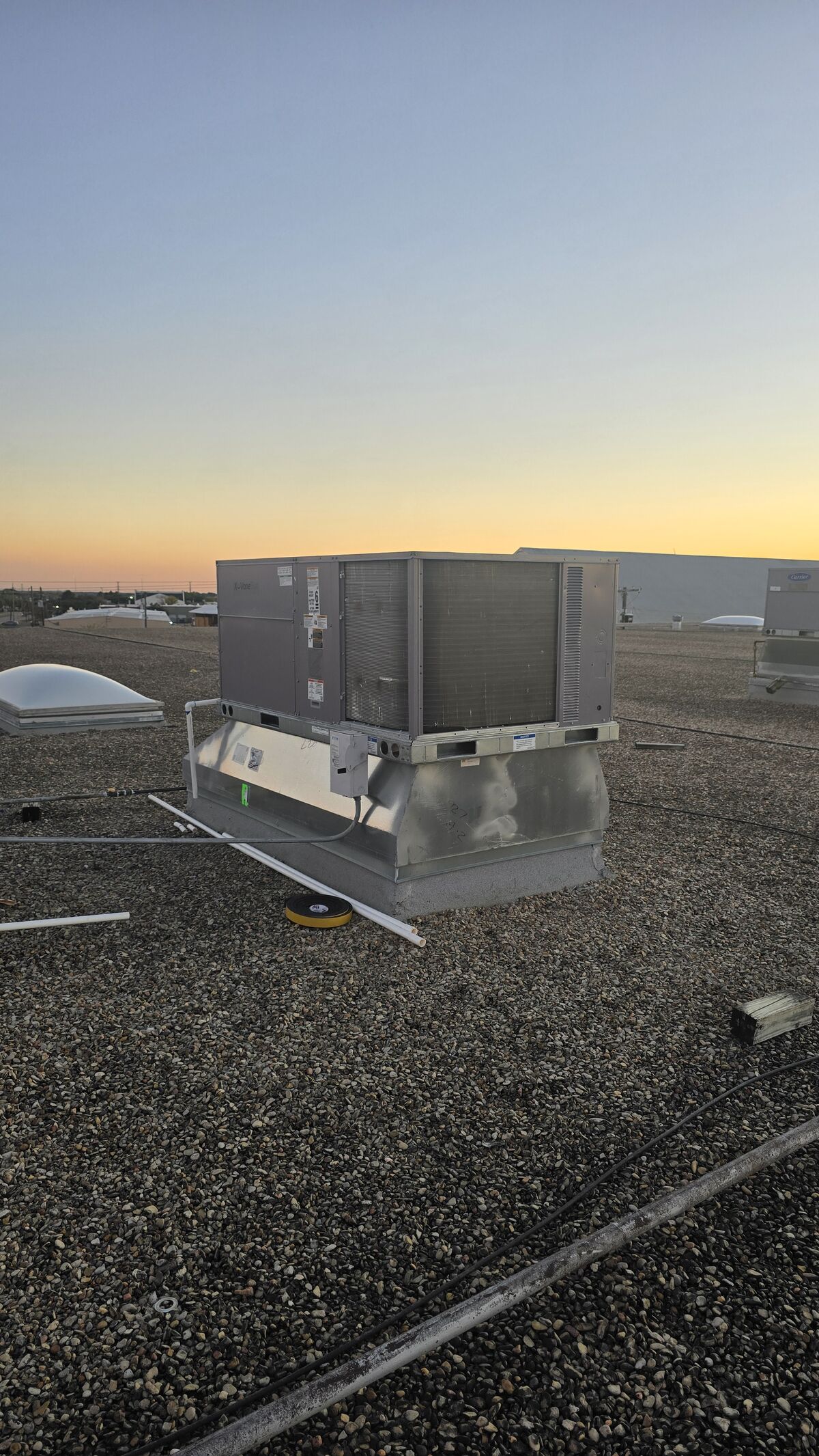Packaged rooftop unit sitting on a gravel commercial roof at dusk